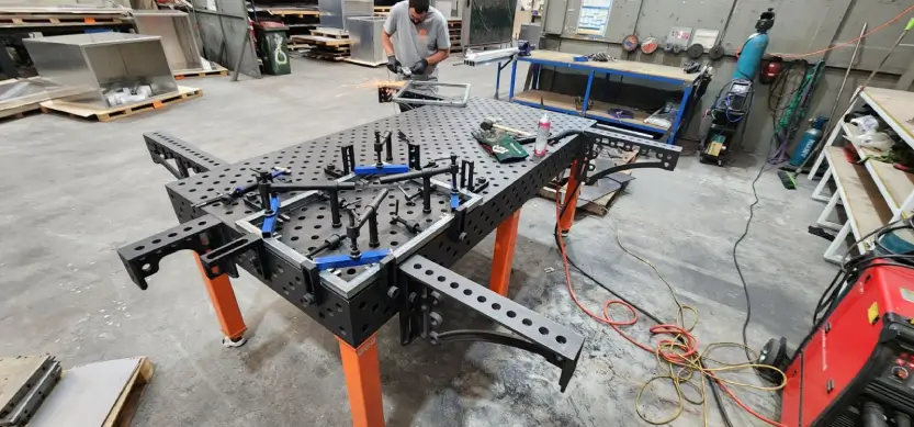 Welding table clamps in use in a fabrication workshop